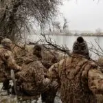 four duck hunters sitting in a duck blind