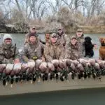 seven men and three dogs showing off their duck hunt results