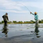 one man fly fishing and the other holding the net