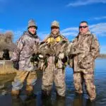 thee men showing off their duck hunt results