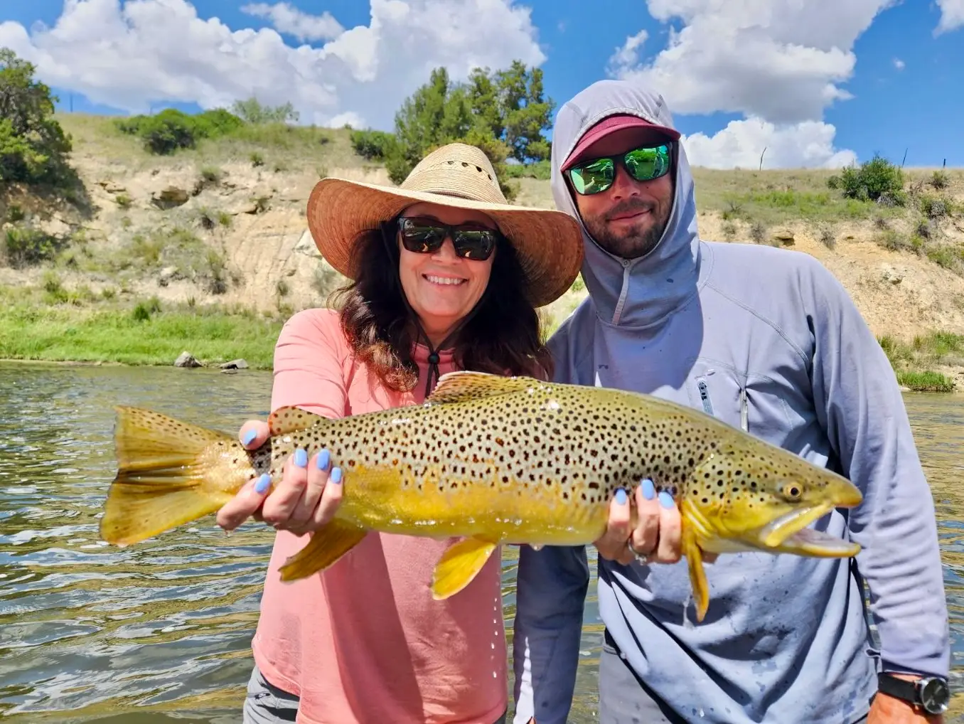 woman holding a fish she caught with man next to her