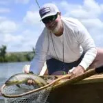 man holding a fish and net smiling