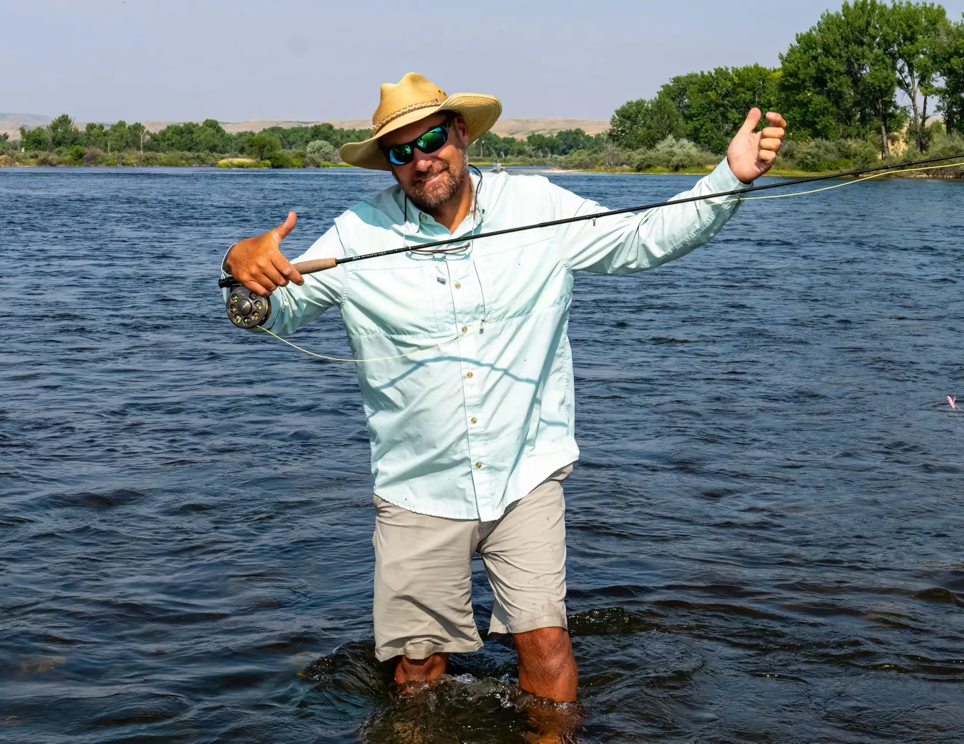 Man wearing shorts fly fishing in the river