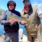 Outfitter with client holding up a recently caught trout caught while fly fishing