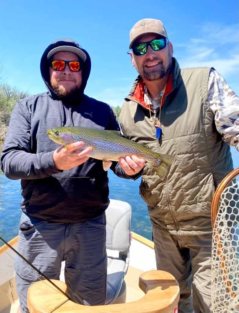 Outfitter with client holding up a recently caught trout caught while fly fishing