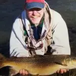 a man smiling while holding a fish