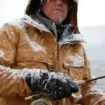 a man covered in frost and snow fly fishing