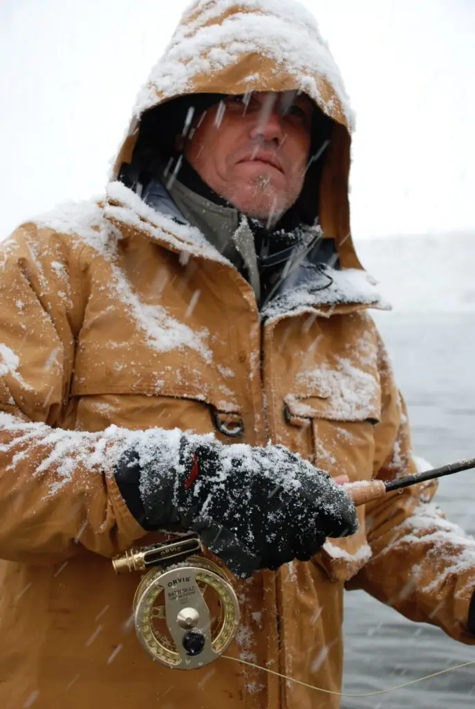 a man covered in frost and snow fly fishing