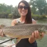 a woman holding a fish with sunglasses on