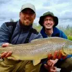 two men wearing hats one is holding a fish