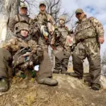 A group of five clients wearing camouflage and showing off their ducks