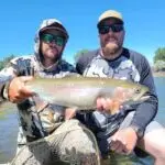 two men with sunglasses one is holding a fish