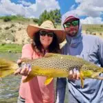 a woman holding a fish with a man next to her