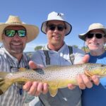 Three anglers with a trout during a guided Bighorn River fly fishing trip