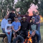 Guests and guides gathered around a campfire at River Rock Lodge in Montana